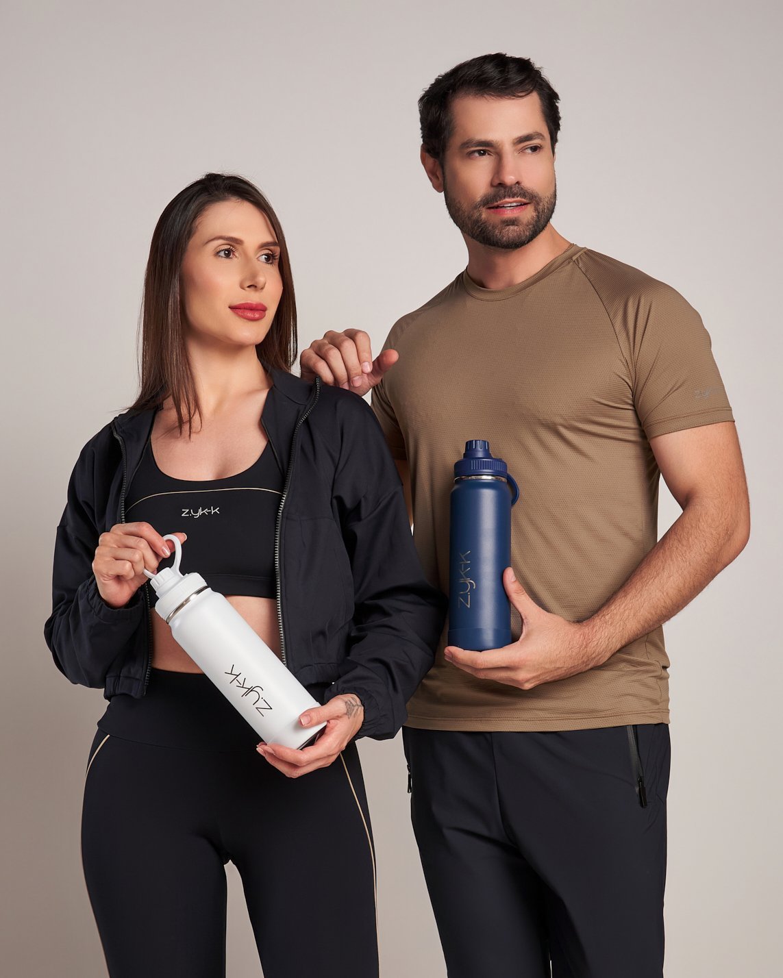 Casal segurando as garrafas térmicas Zykk de 800 ml, branca e azul